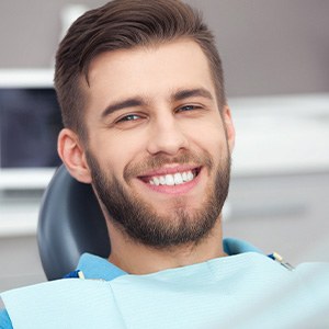 Bearded man sitting in dental chair and smiling