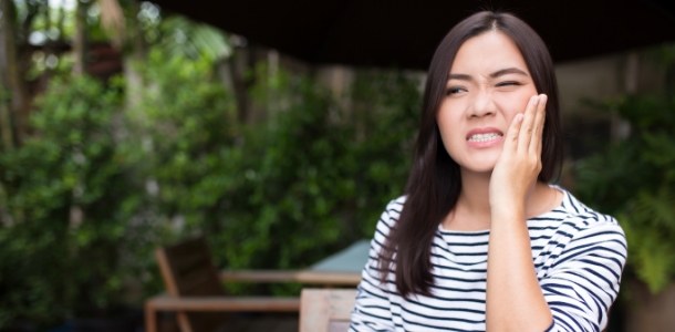 Woman holding her cheek in pain before emergency dentistry in Heber City