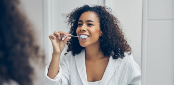 Woman smiling while brushing her teeth