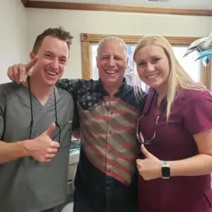 Two dental team members giving thumbs up with a patient