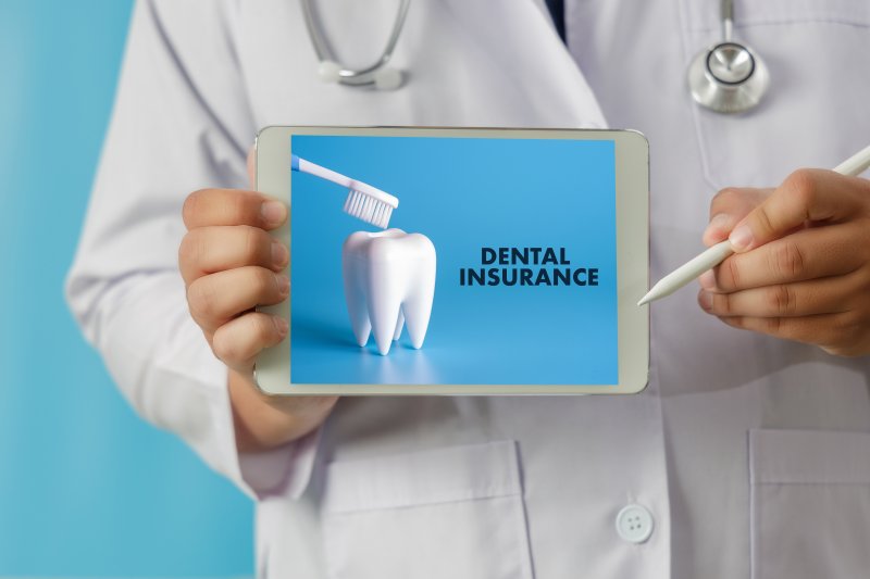 dentist holding tablet that reads Dental Insurance